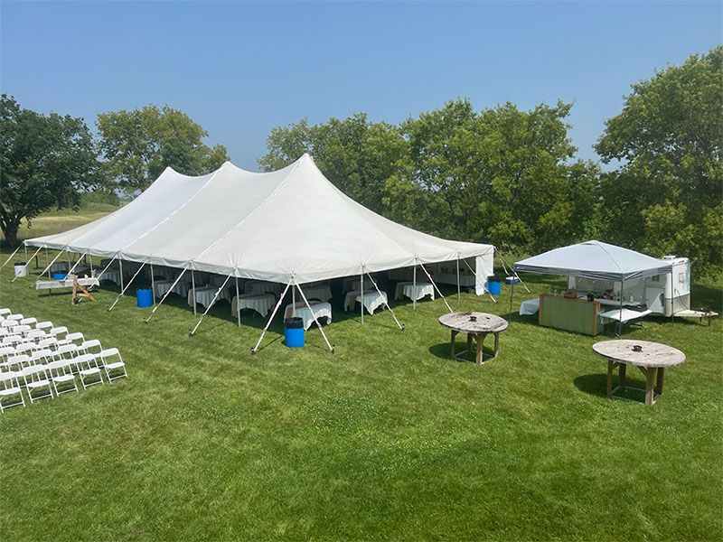 A large white tent is sitting in the middle of a grassy field.