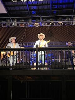 A man in a cowboy hat is playing a guitar on a stage.