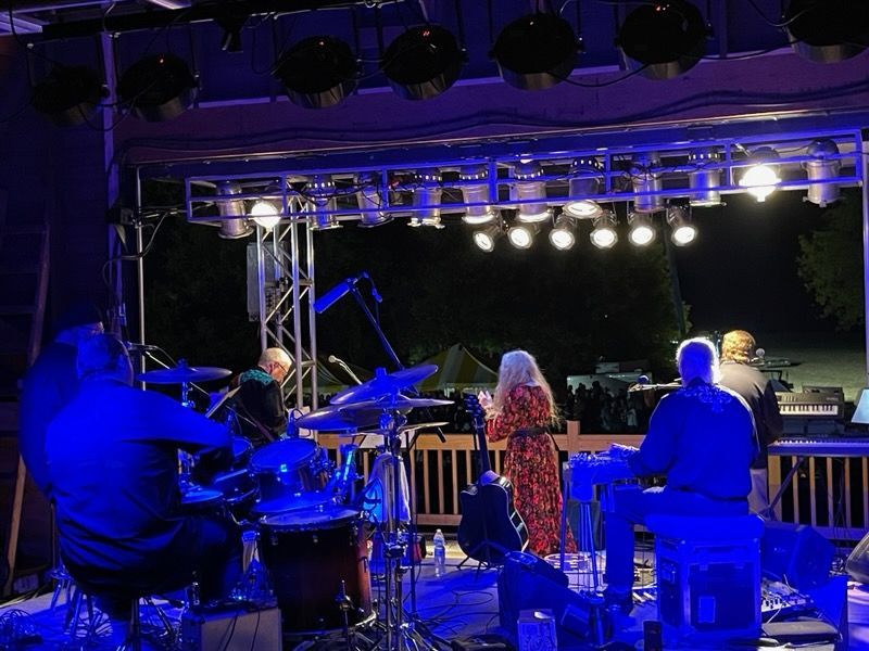 A group of people are playing instruments on a stage at night.