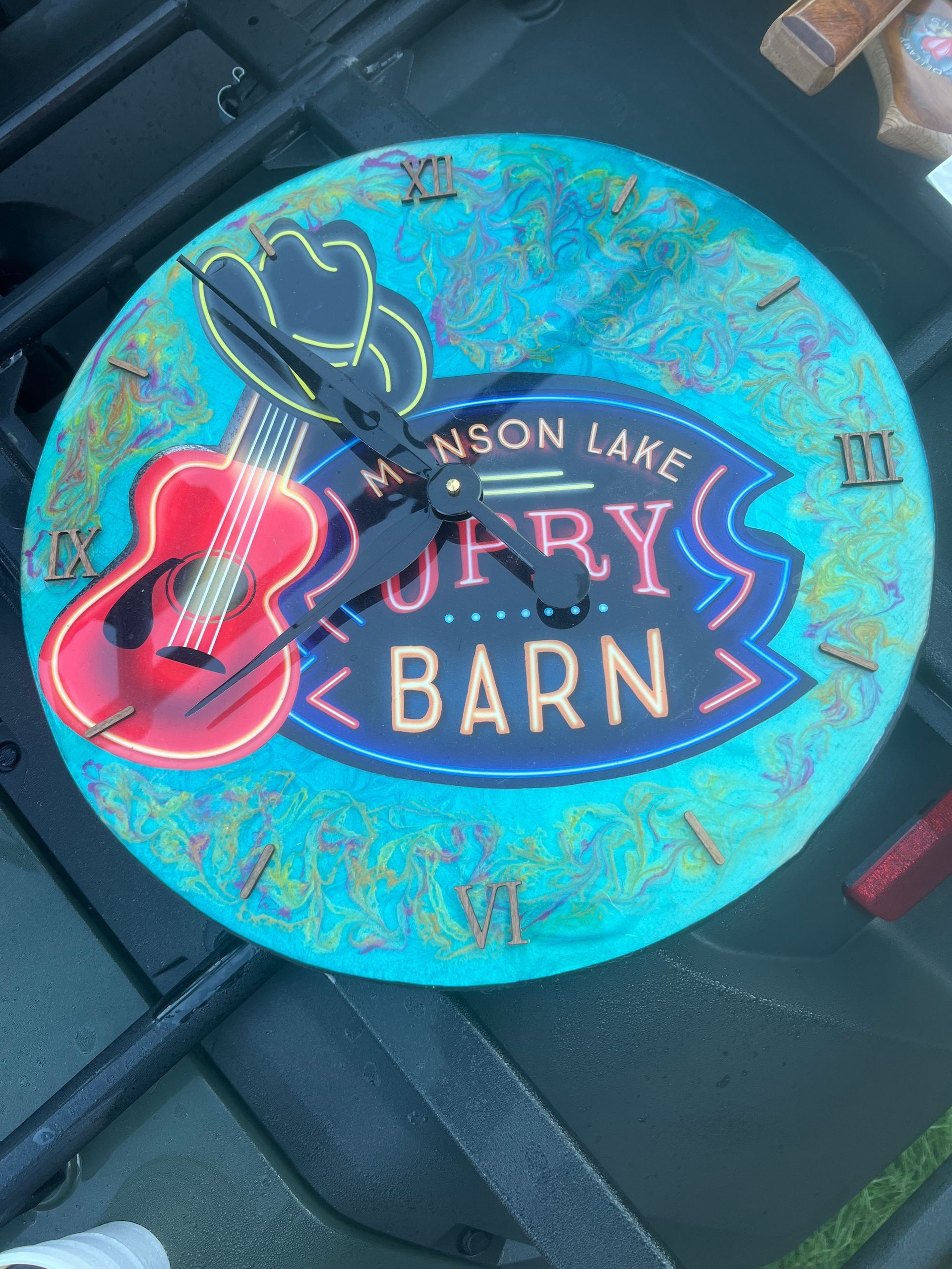 Blue round sign for Mason Lake Surry Barn with a pink guitar and cowboy boots.