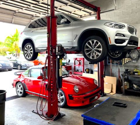 A red car is sitting on a lift in a garage.