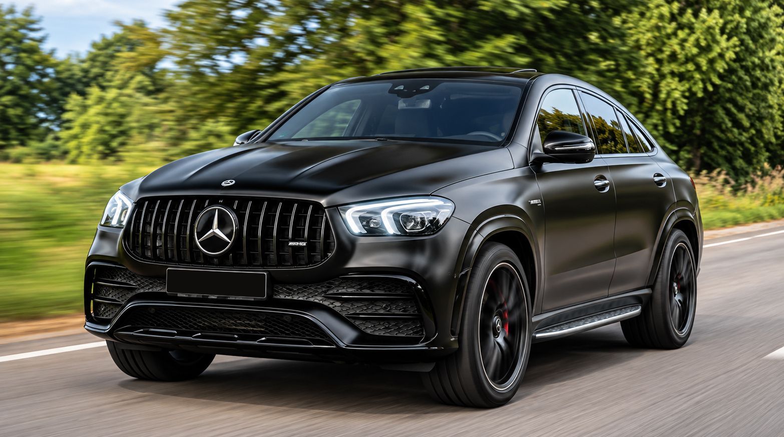 Black Mercedes SUV driving on a road with trees in the background