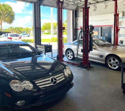 Two cars are sitting on a lift in a garage.