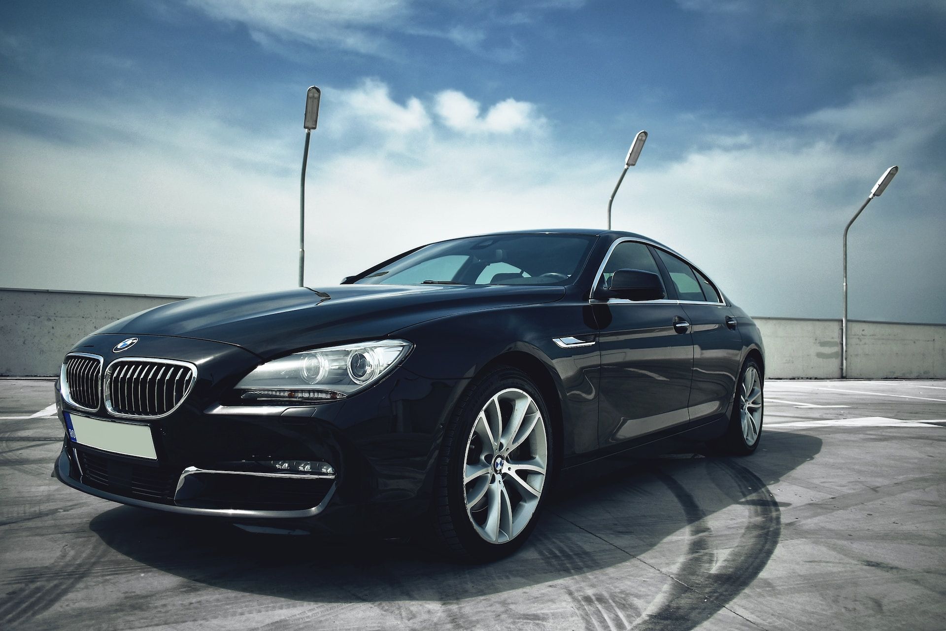 A black bmw is parked in a parking lot.