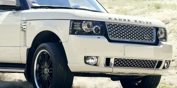 A white range rover is parked in the dirt