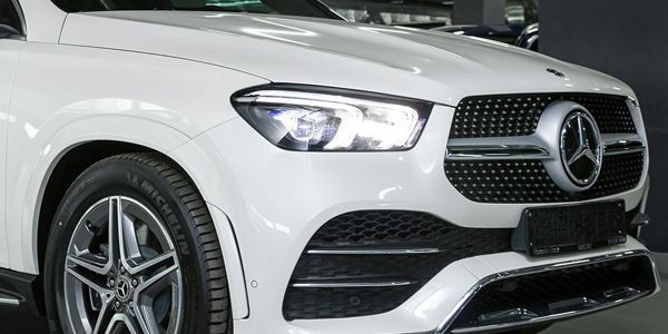A white mercedes benz gle suv is parked in a showroom.