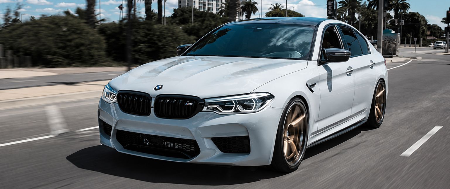 White BMW sedan driving on a sunlit city street