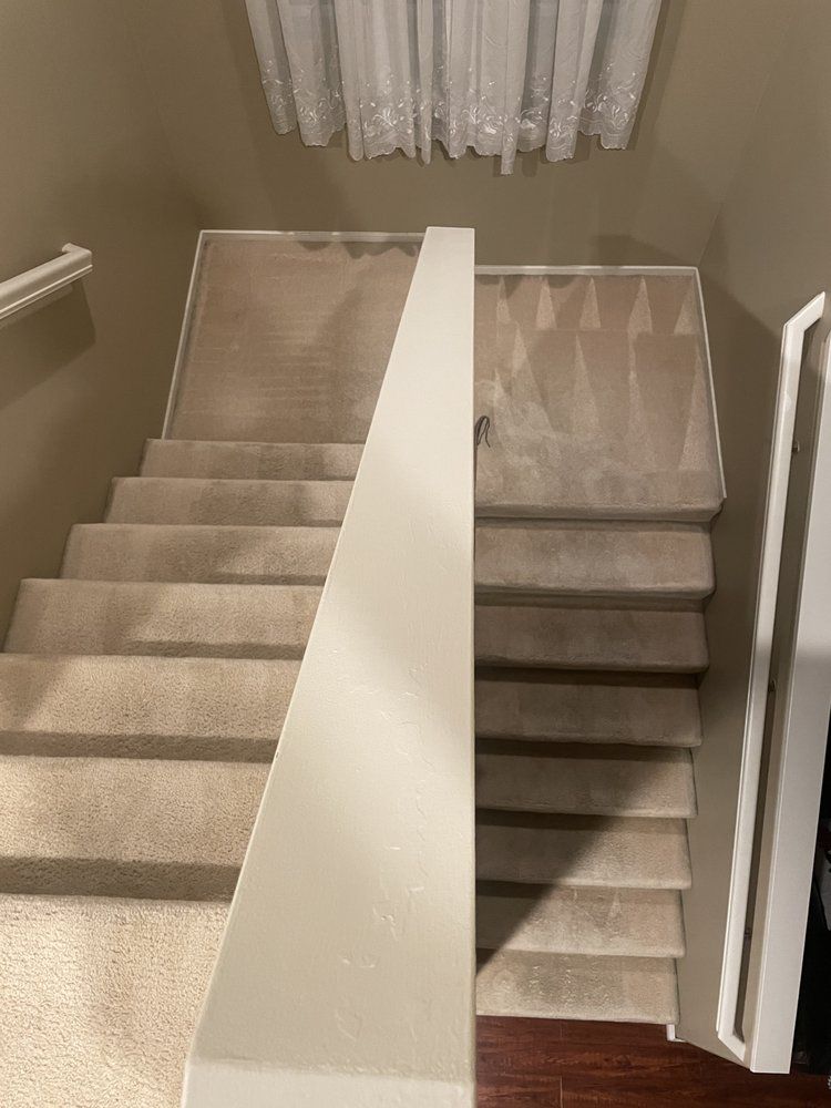 A staircase with a white railing and carpeted steps in a house.