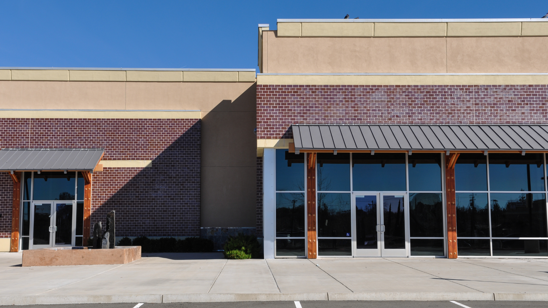Glass storefront entrance with wooden-framed doors and reflections of the street outside