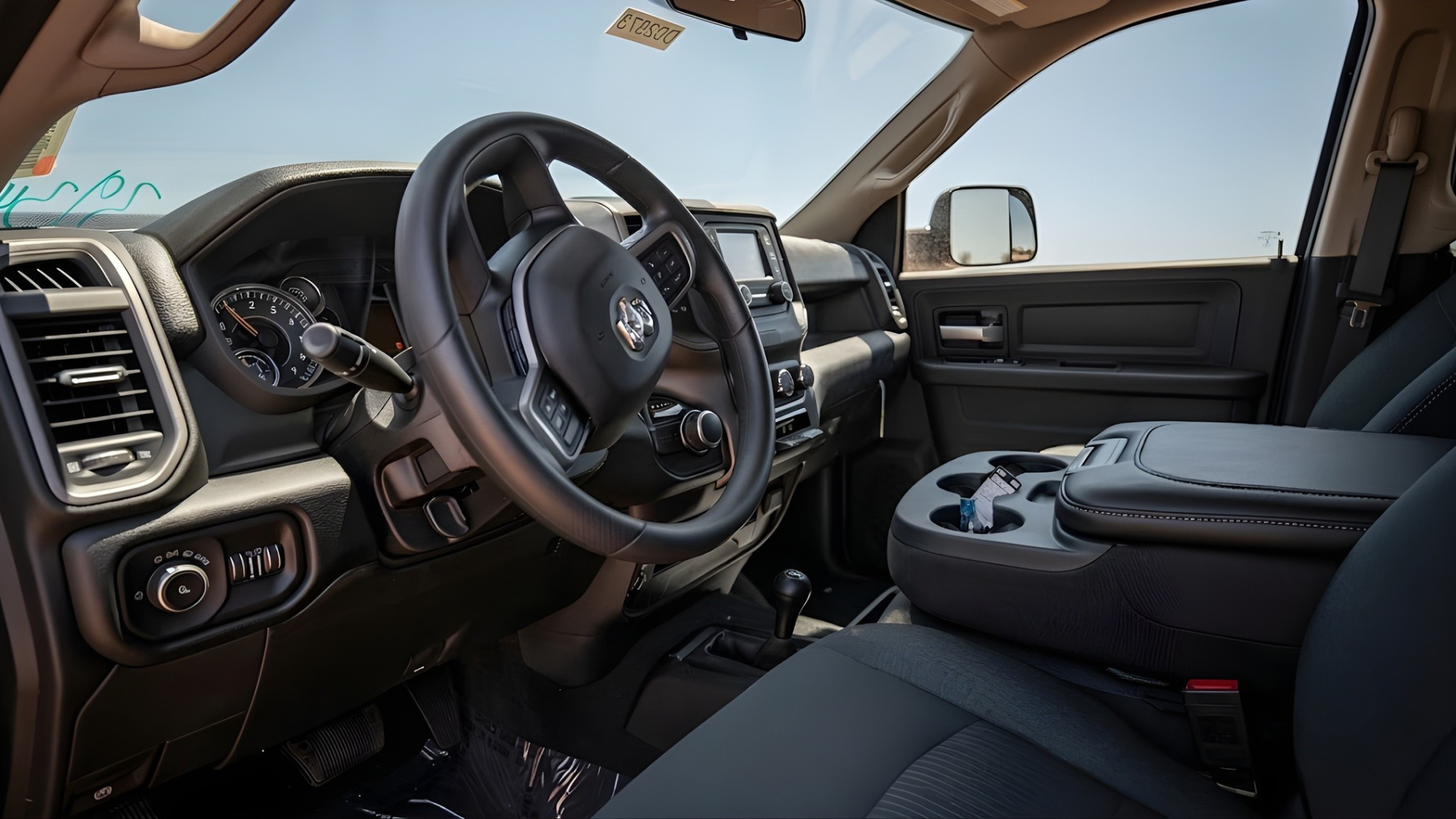 Black truck interior with steering wheel, dashboard, and center console in daylight
