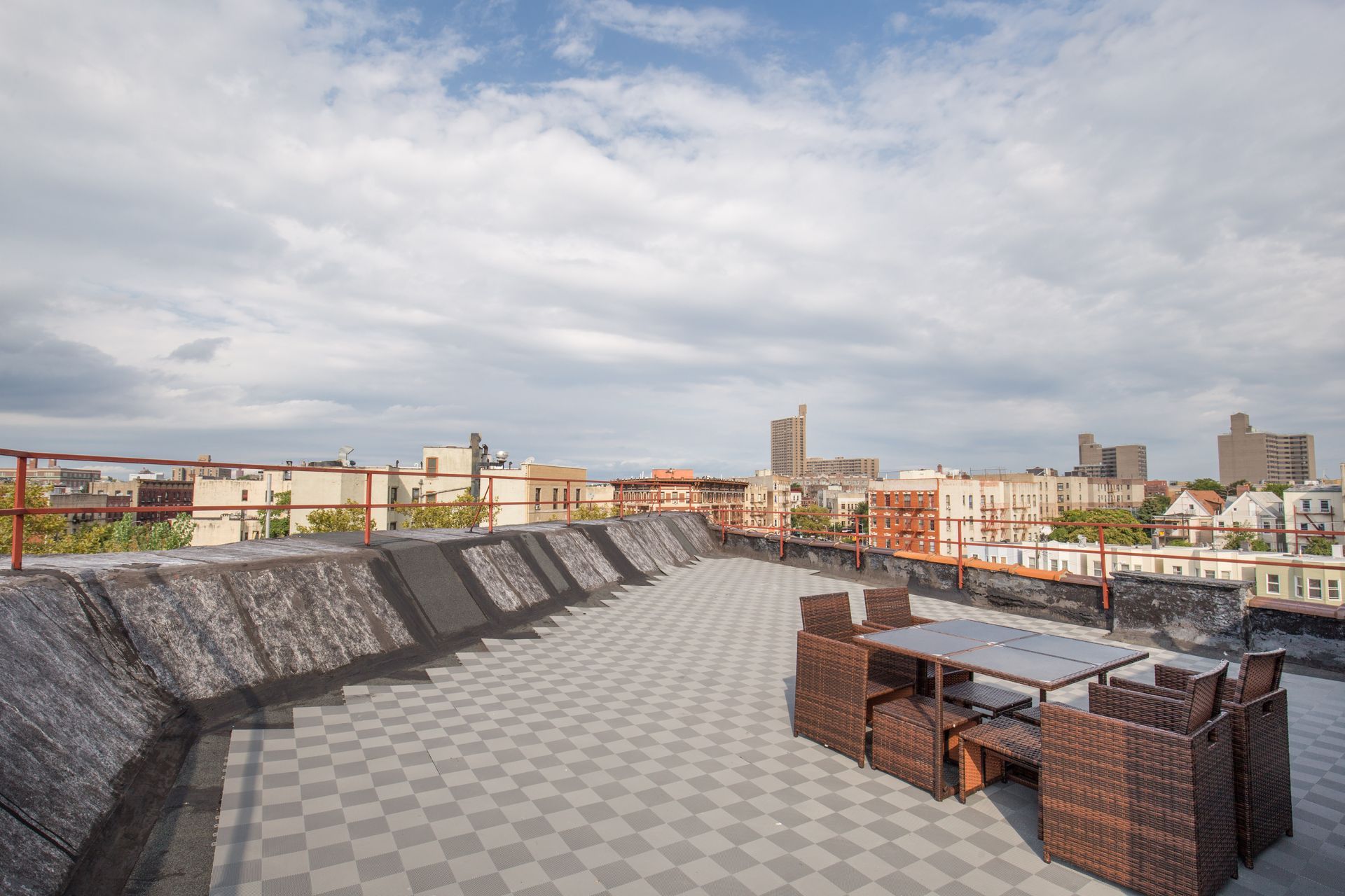 A rooftop deck with a table and chairs and a view of the city.