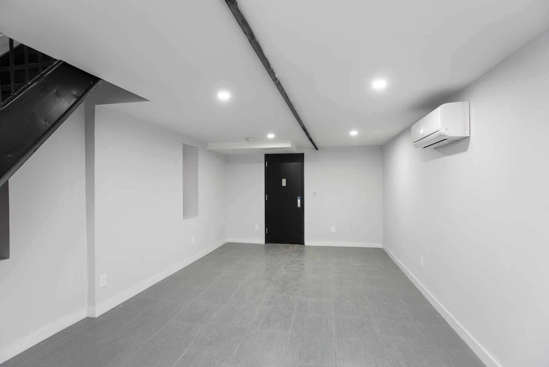 An empty room with white walls and a black door.