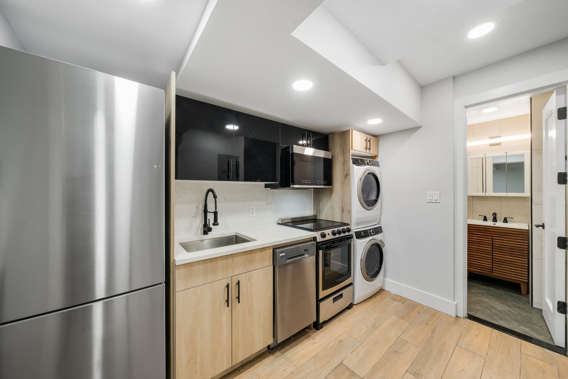 A kitchen with stainless steel appliances and a stack of washers and dryers.