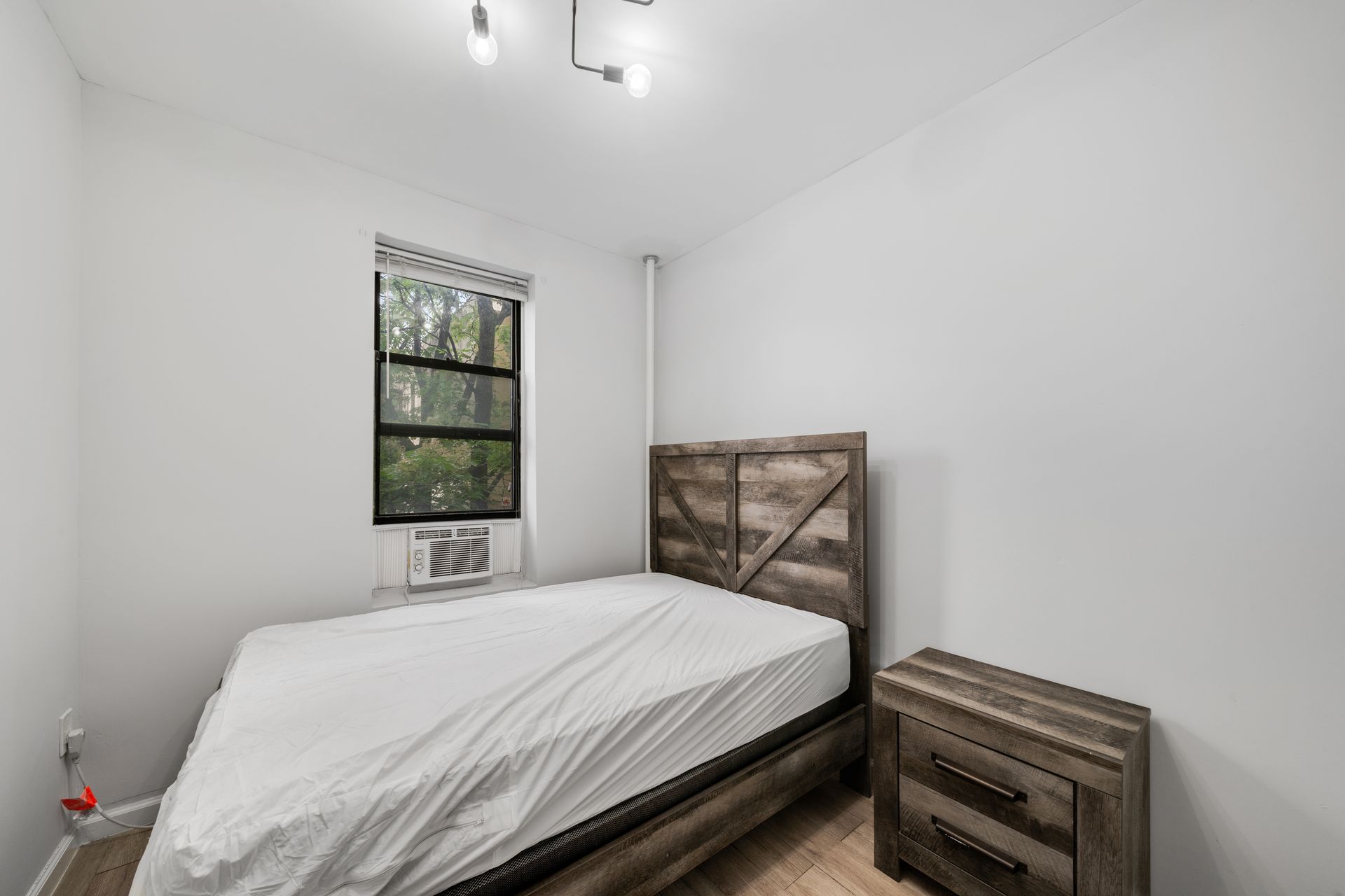 A bedroom with a bed , nightstand , and window.