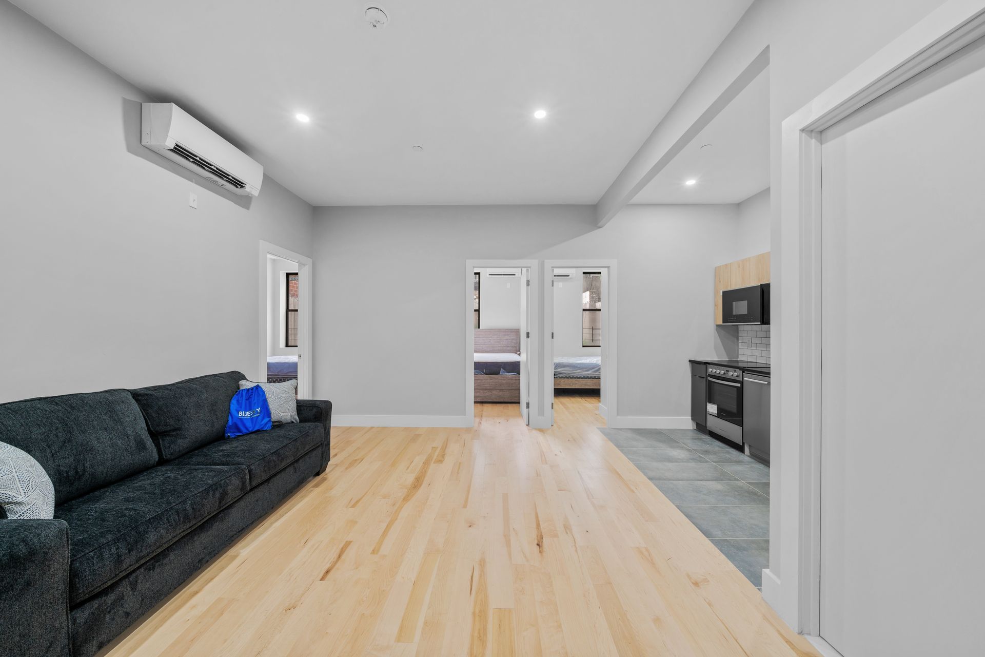 A living room with a couch , air conditioner , and hardwood floors.