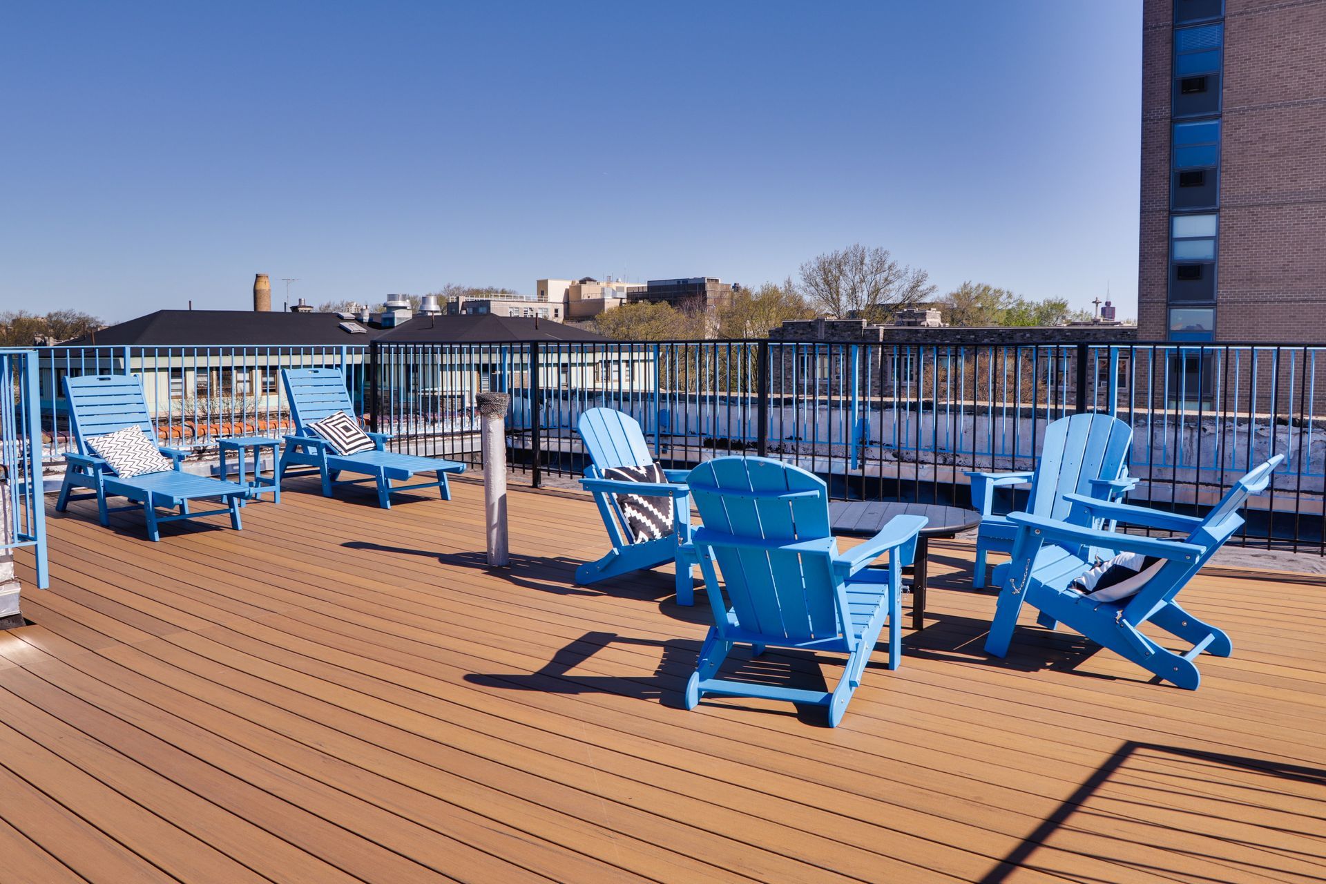 A deck with blue chairs and lounge chairs on it
