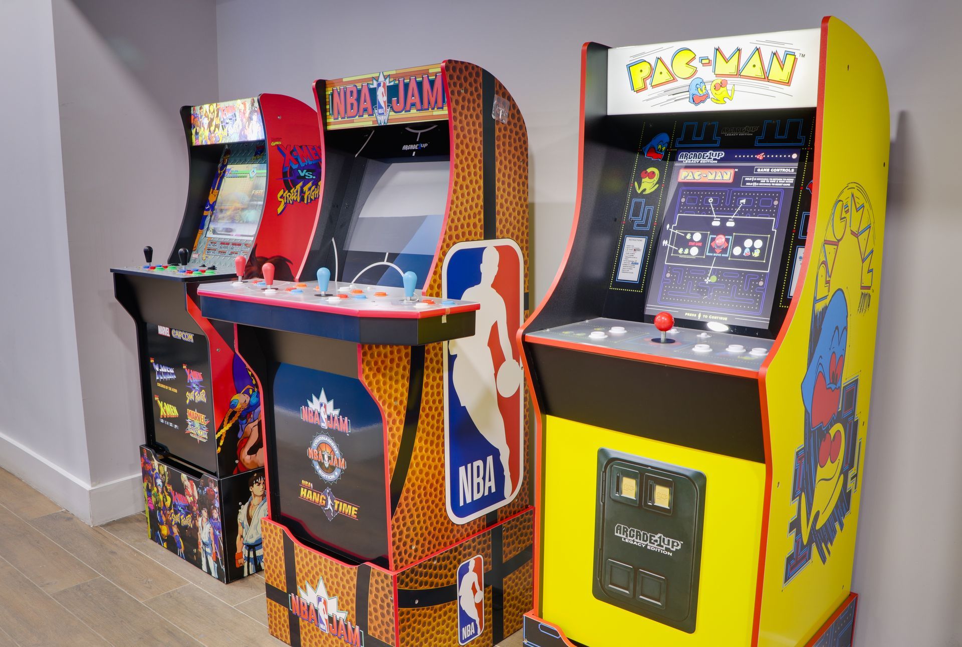 Three arcade machines are lined up next to each other in a room.