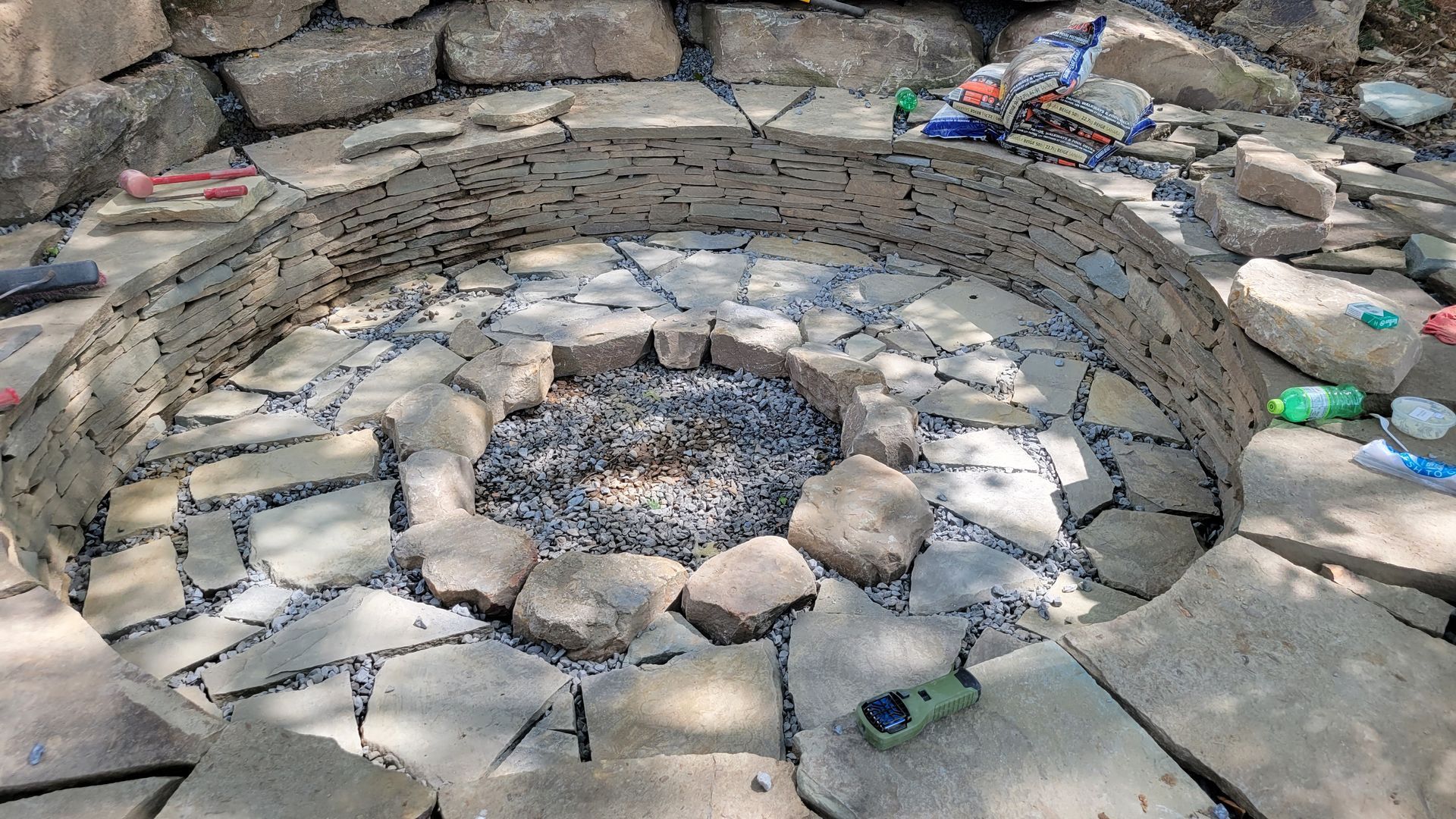 a fire pit is surrounded by rocks and a stone wall .