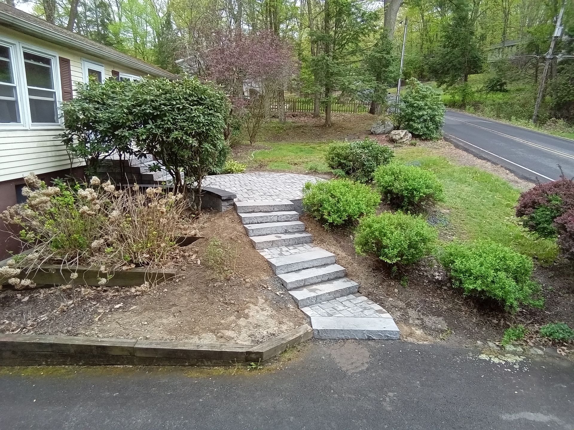 A house with stairs leading up to it and a road in the background.