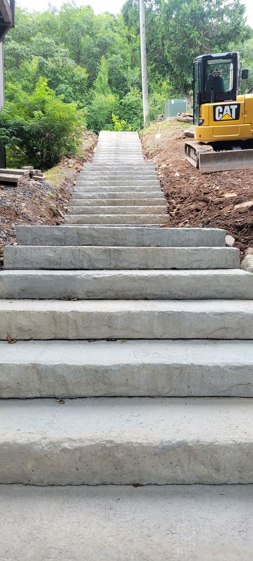 A cat bulldozer is driving down a set of concrete stairs.