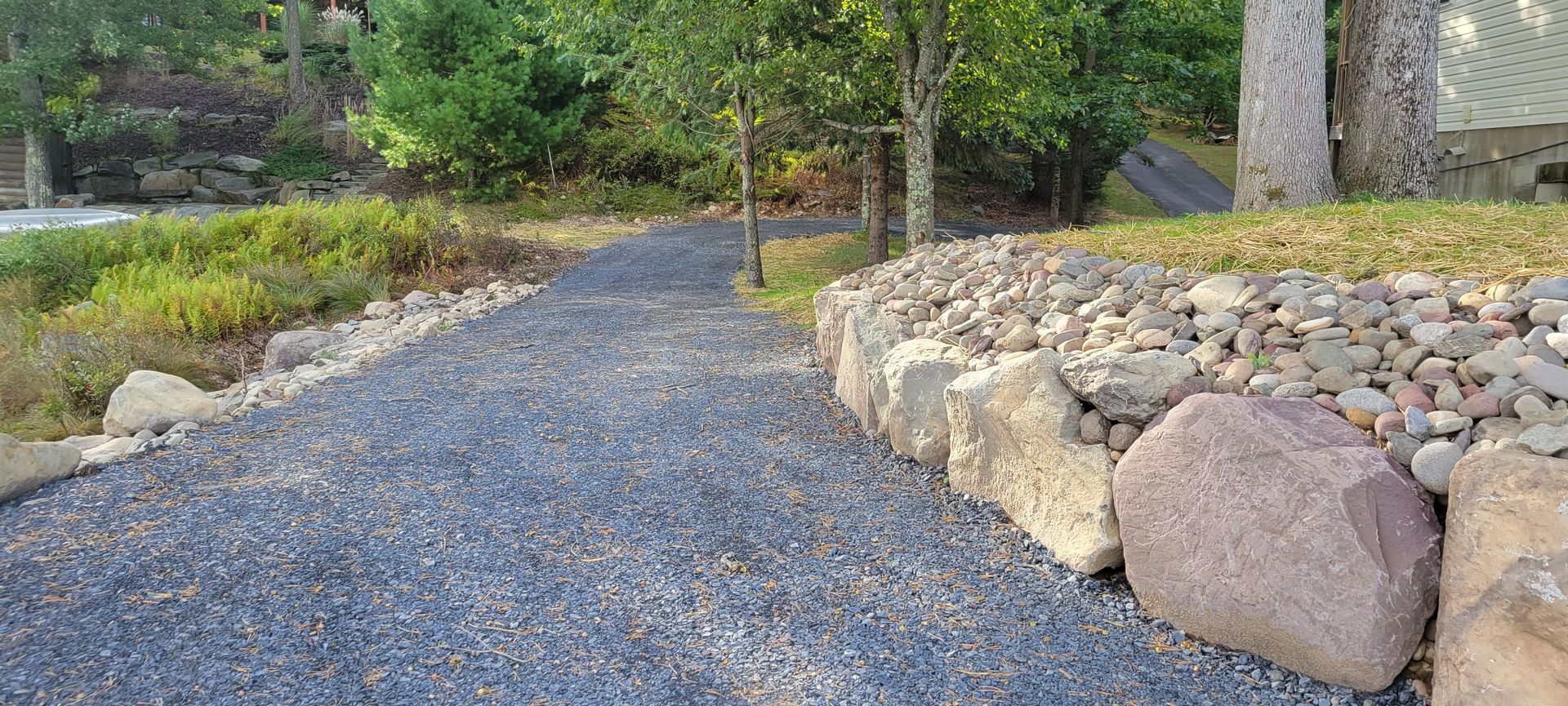 a gravel path surrounded by rocks and trees in a park .