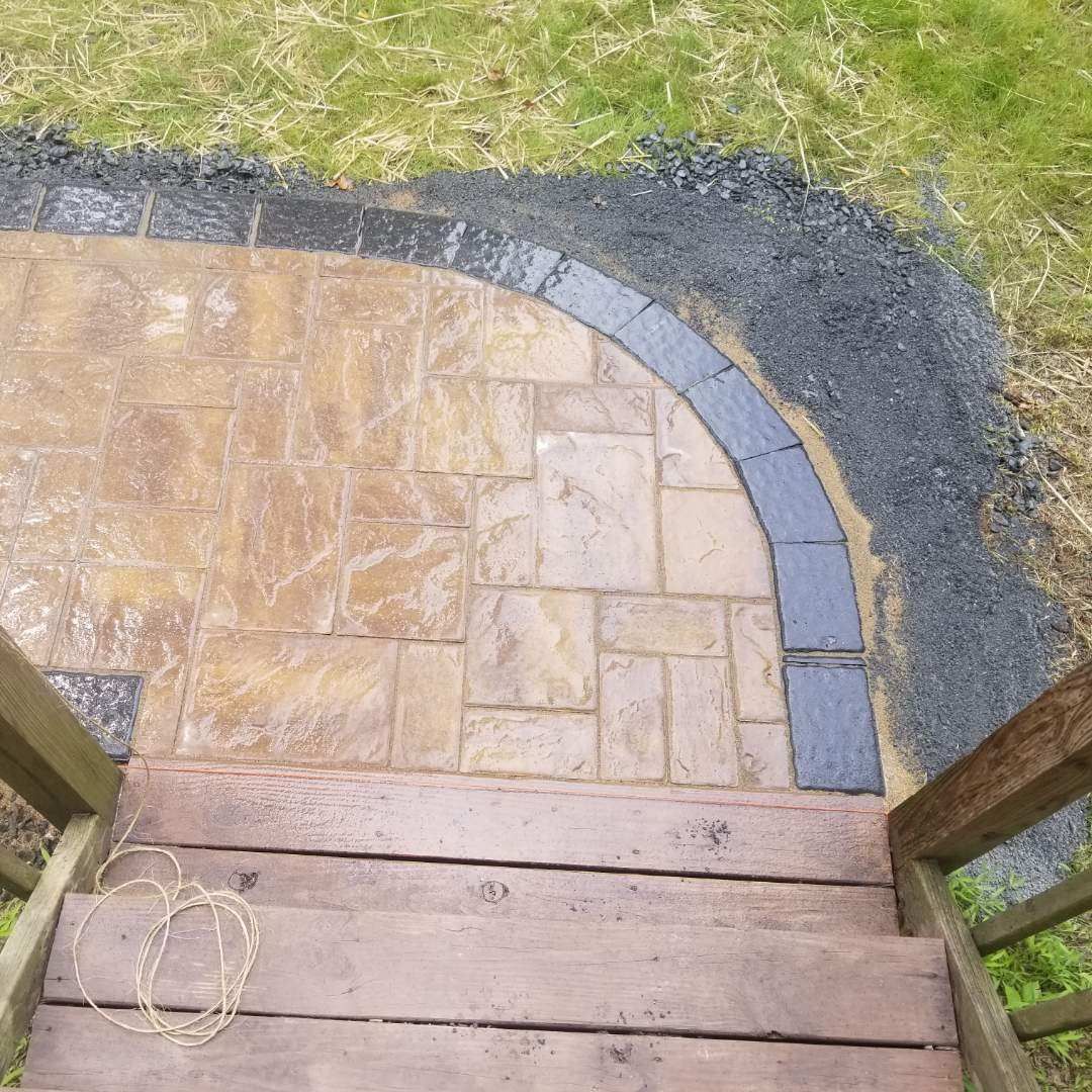a wooden staircase leading up to a brick walkway surrounded by grass .