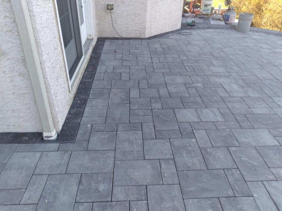 A brick walkway is being built on the side of a house.