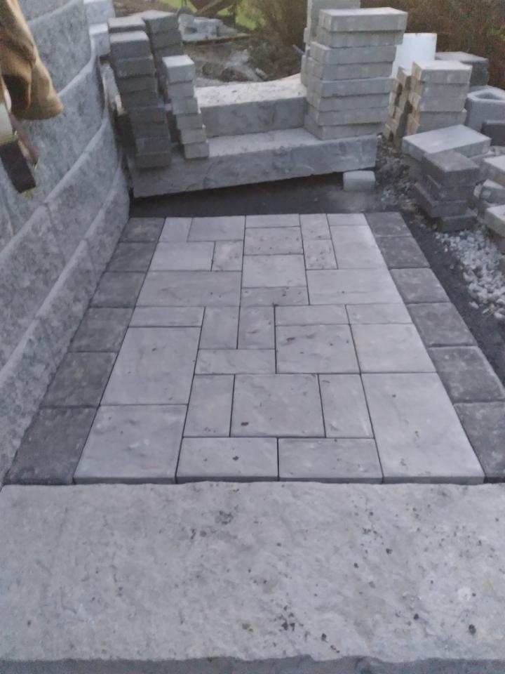 a brick walkway is being built next to a brick wall by A.A.F Landscaping