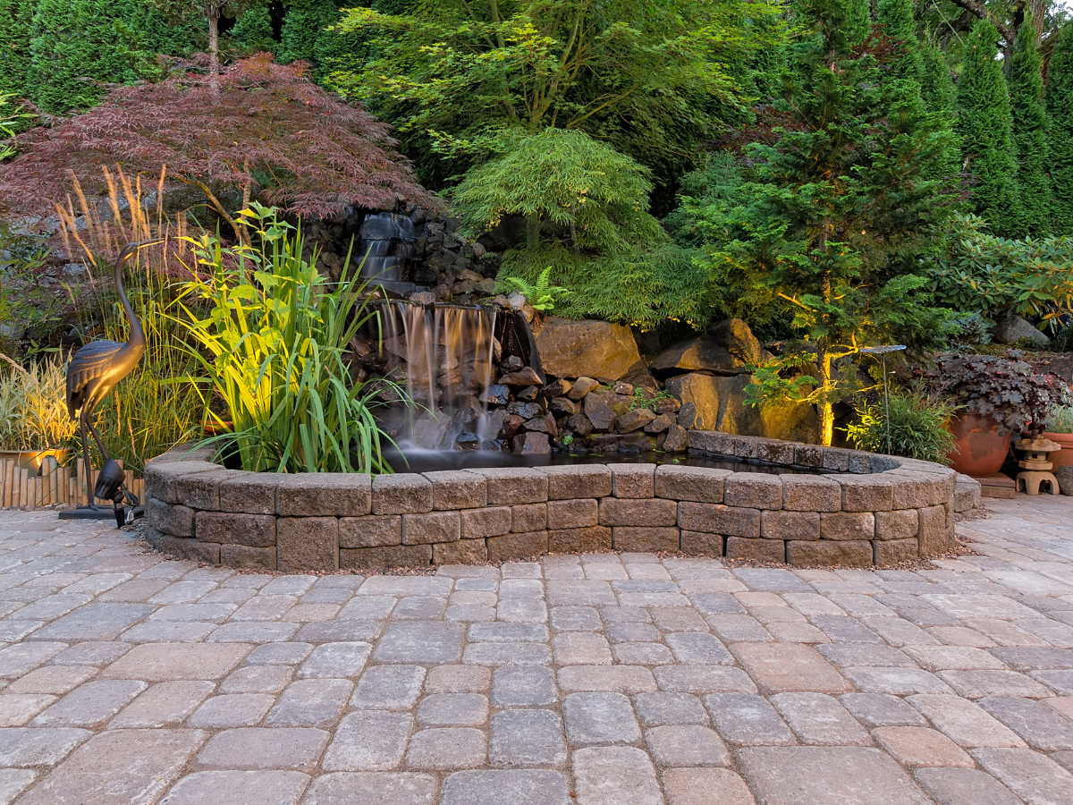 A brick patio with a waterfall in the background.