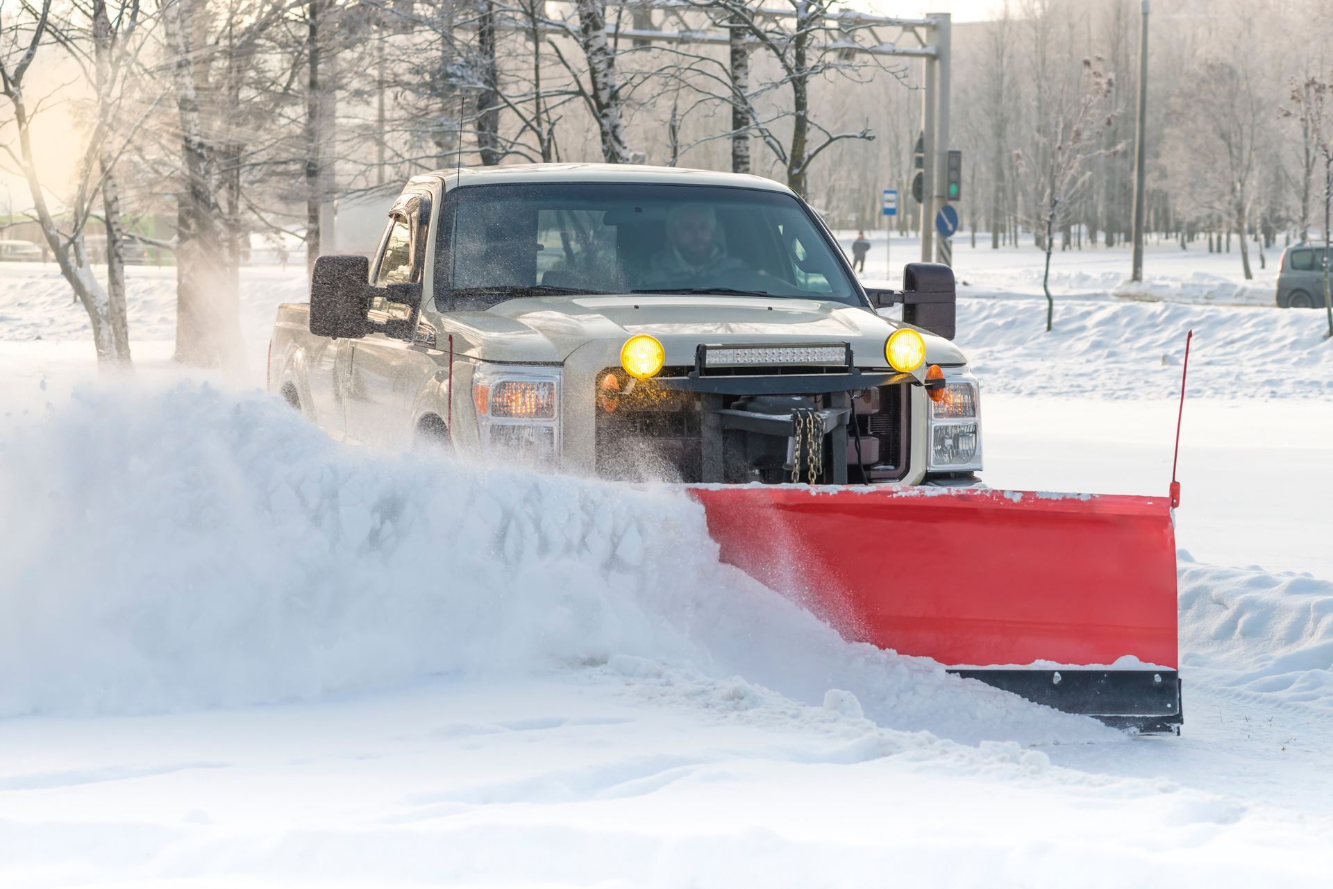 Snowplow truck clearing snow from a road, spraying snow outwards, on a sunny day. Snowplow truck clearing snow from a road, spraying snow outwards, on a sunny day.