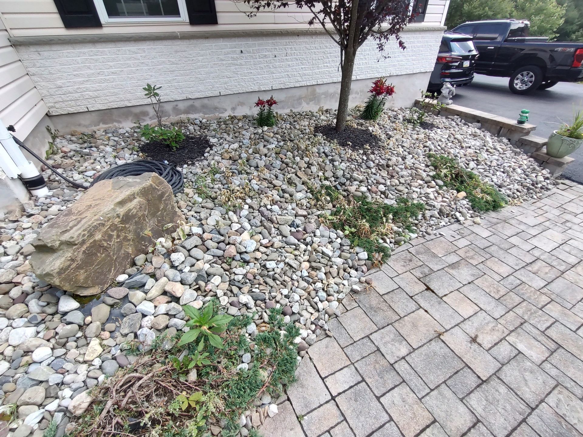 a driveway with trees and flowers in front of a building