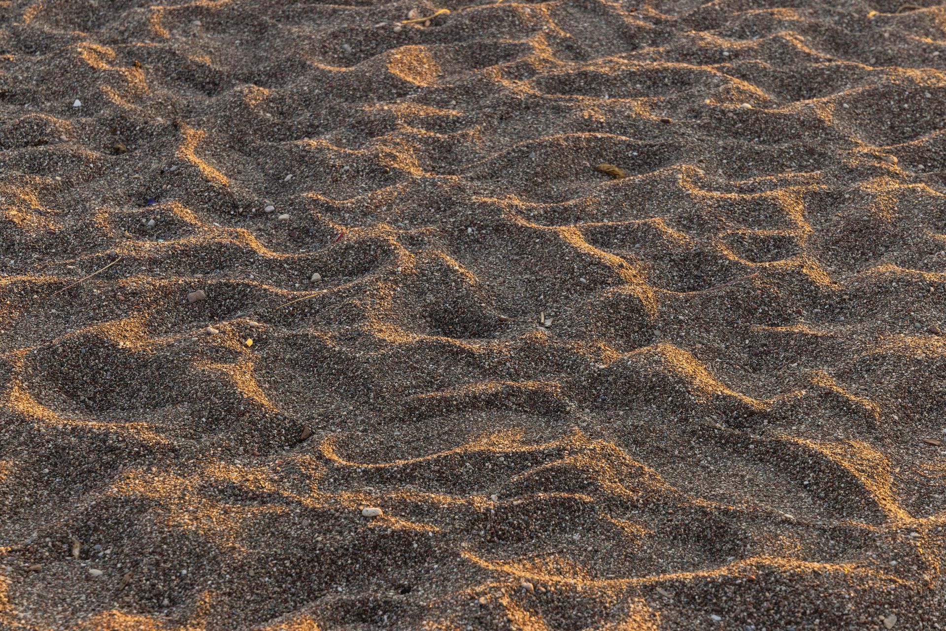 Black sand with golden highlights, rippled texture.