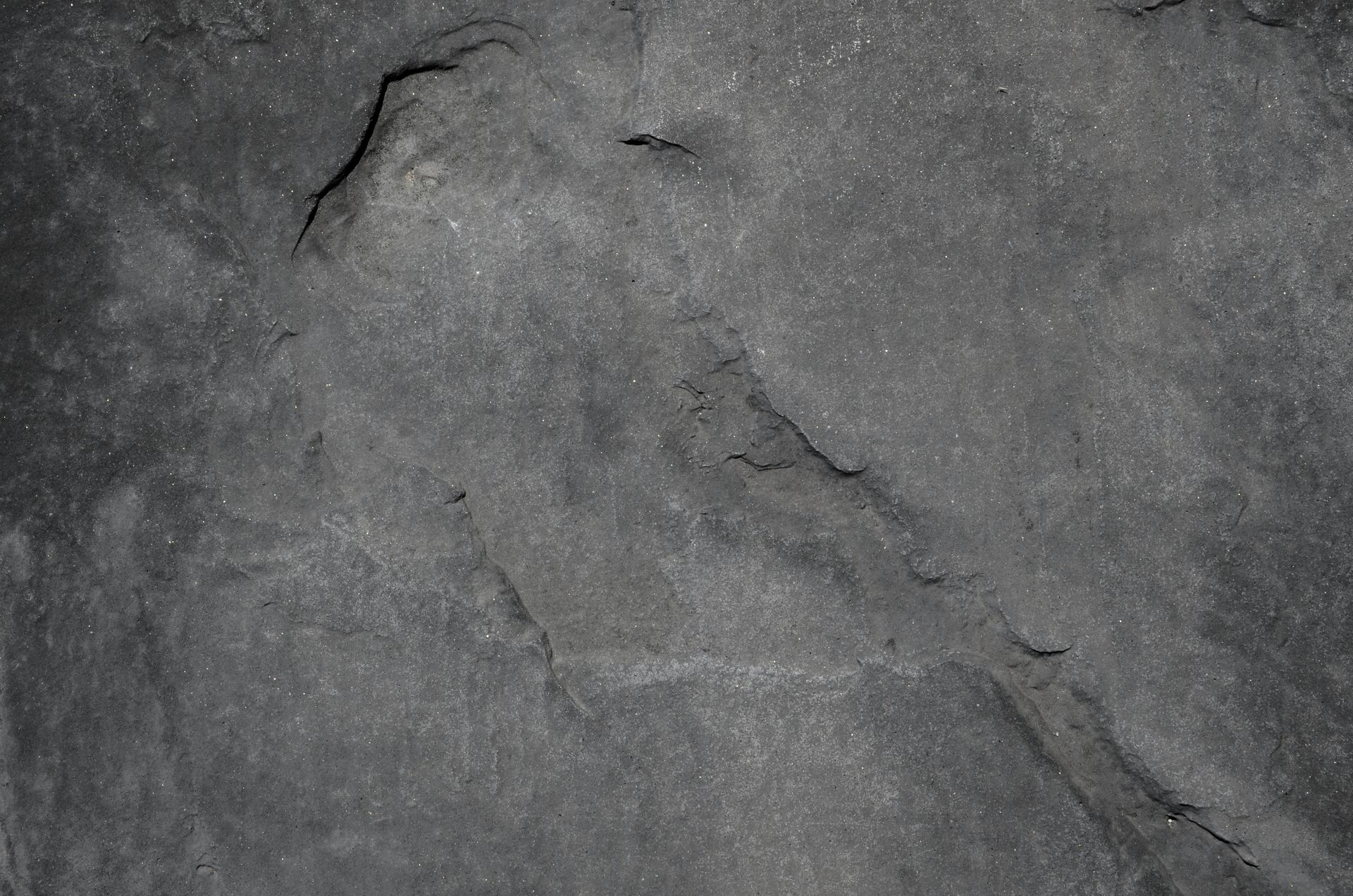 Gray textured rock surface with cracks.