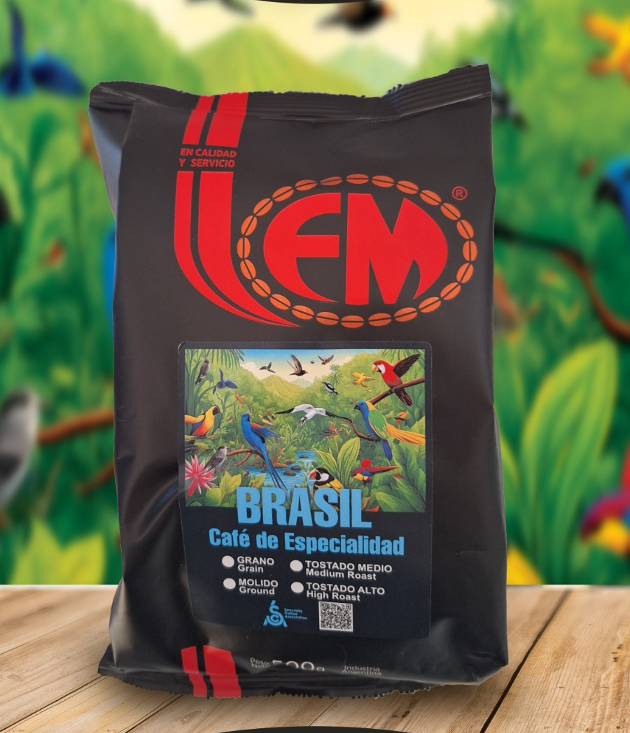 Una bolsa de café negra con el logotipo rojo de FM y una colorida etiqueta de Brasil sobre una mesa de madera.