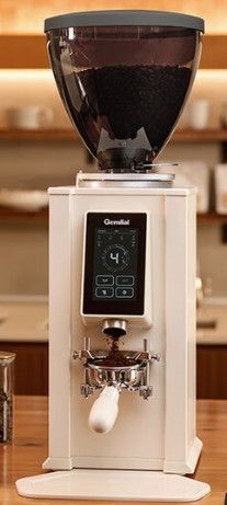 Molinillo de café blanco sobre el mostrador de una cafetería con granos de café, tazas