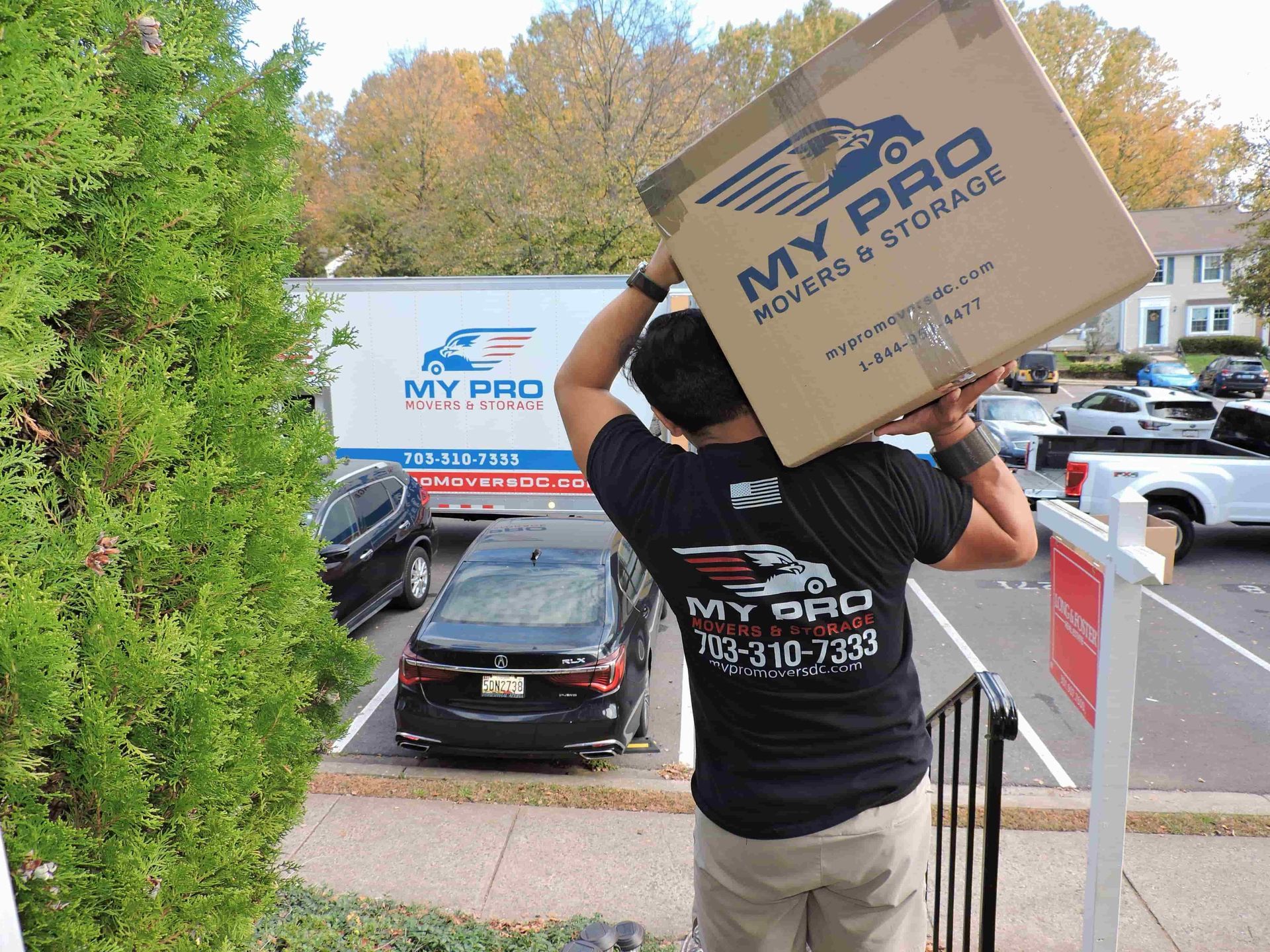 Mover carrying a My Pro Moving box down outdoor stairs at a house entry