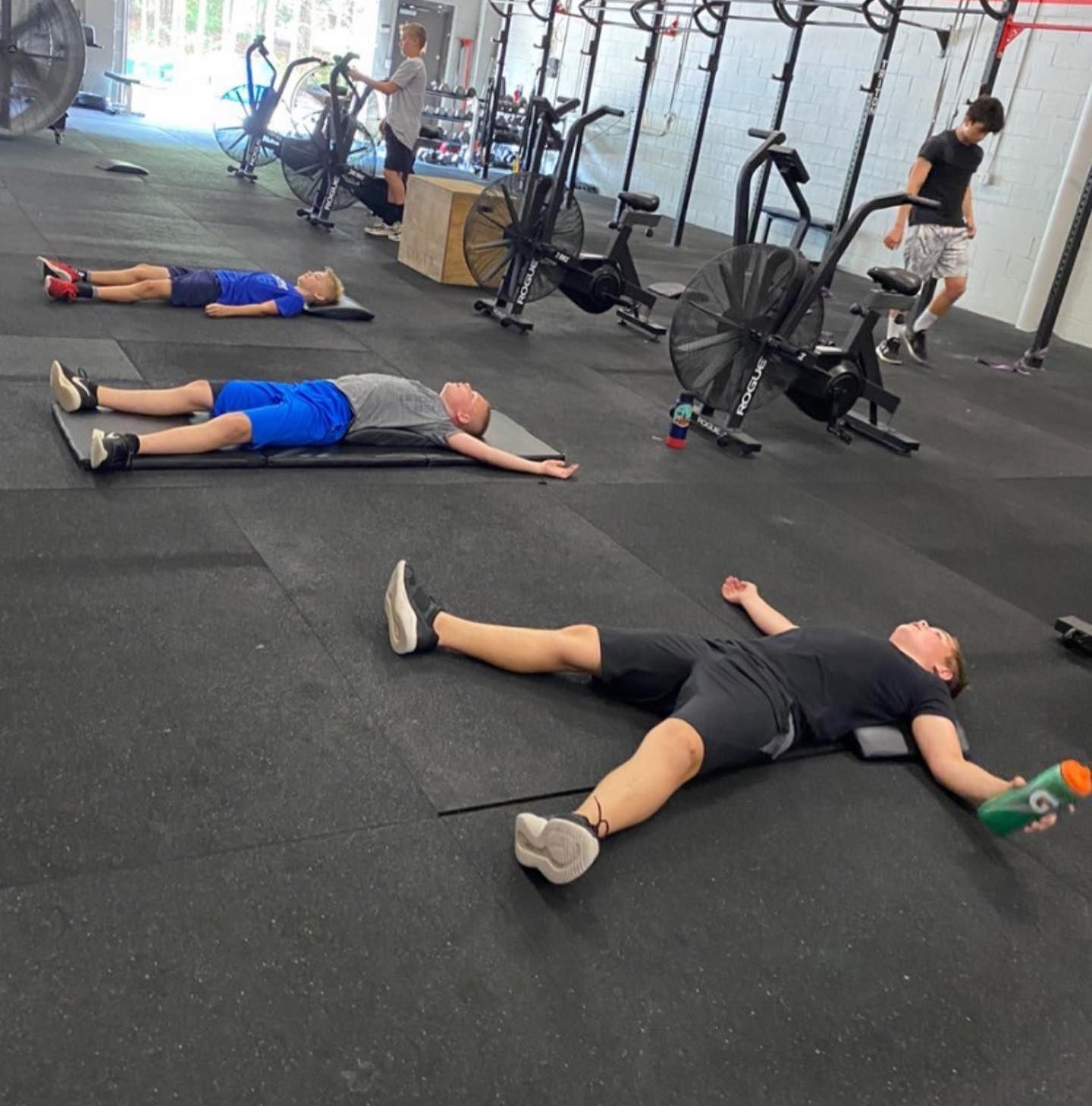 A group of people are laying on the floor in a gym
