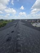 Rooftop with dark gravel under a cloudy sky, overlooking houses and trees in the distance