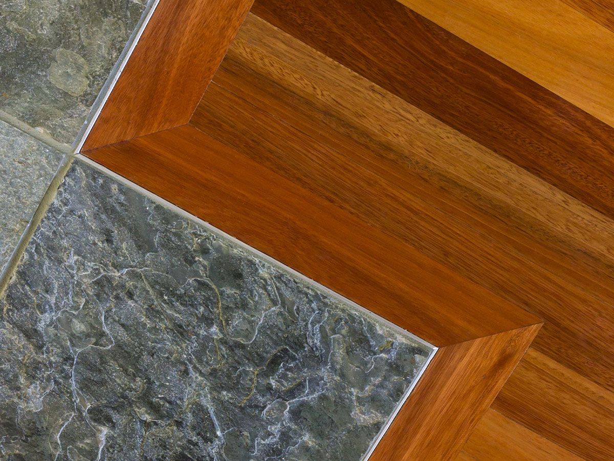 A close up of a wooden floor with a tile border
