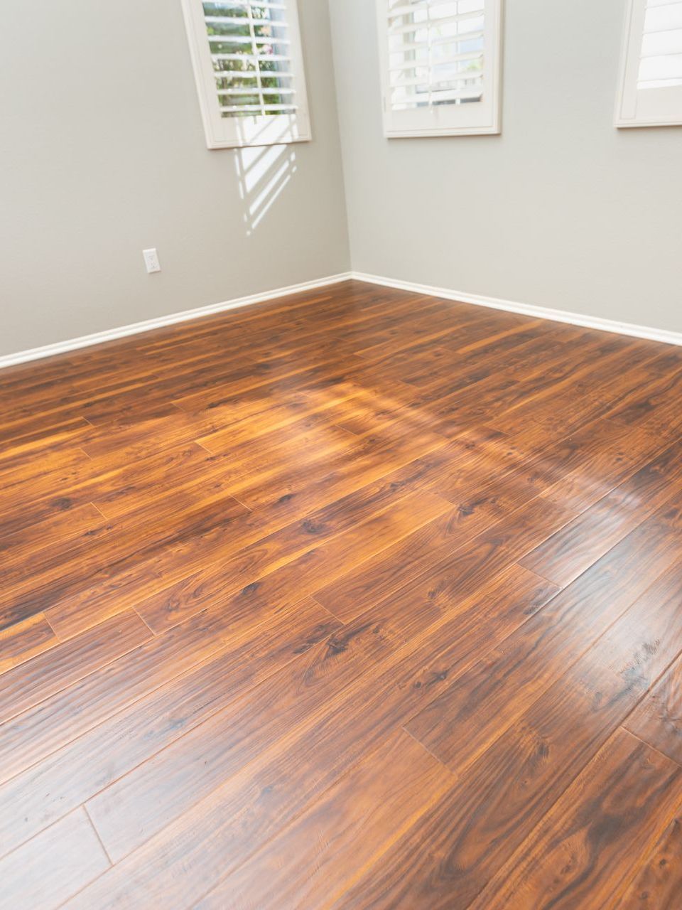 An empty room with hardwood floors and shutters on the windows.