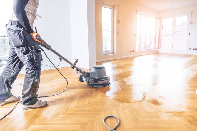 A man is polishing a wooden floor with a machine.