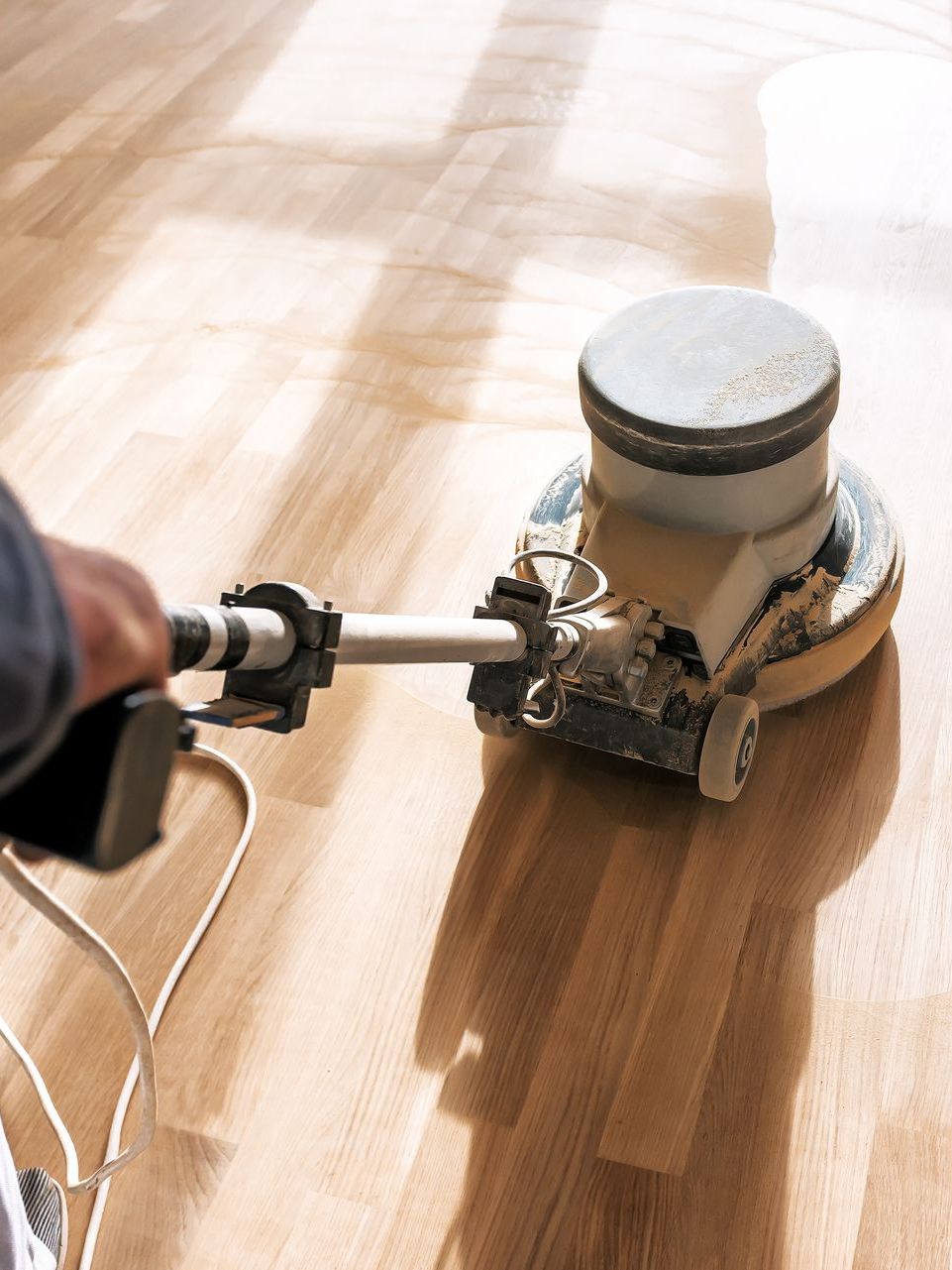 A person is using a machine to polish a wooden floor.
