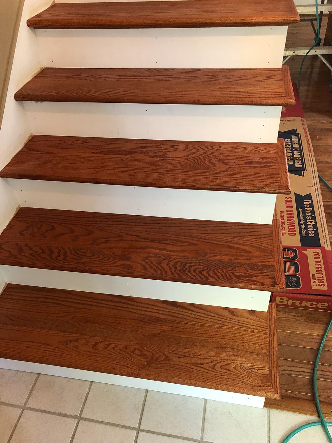 A set of wooden stairs with a hose next to them.