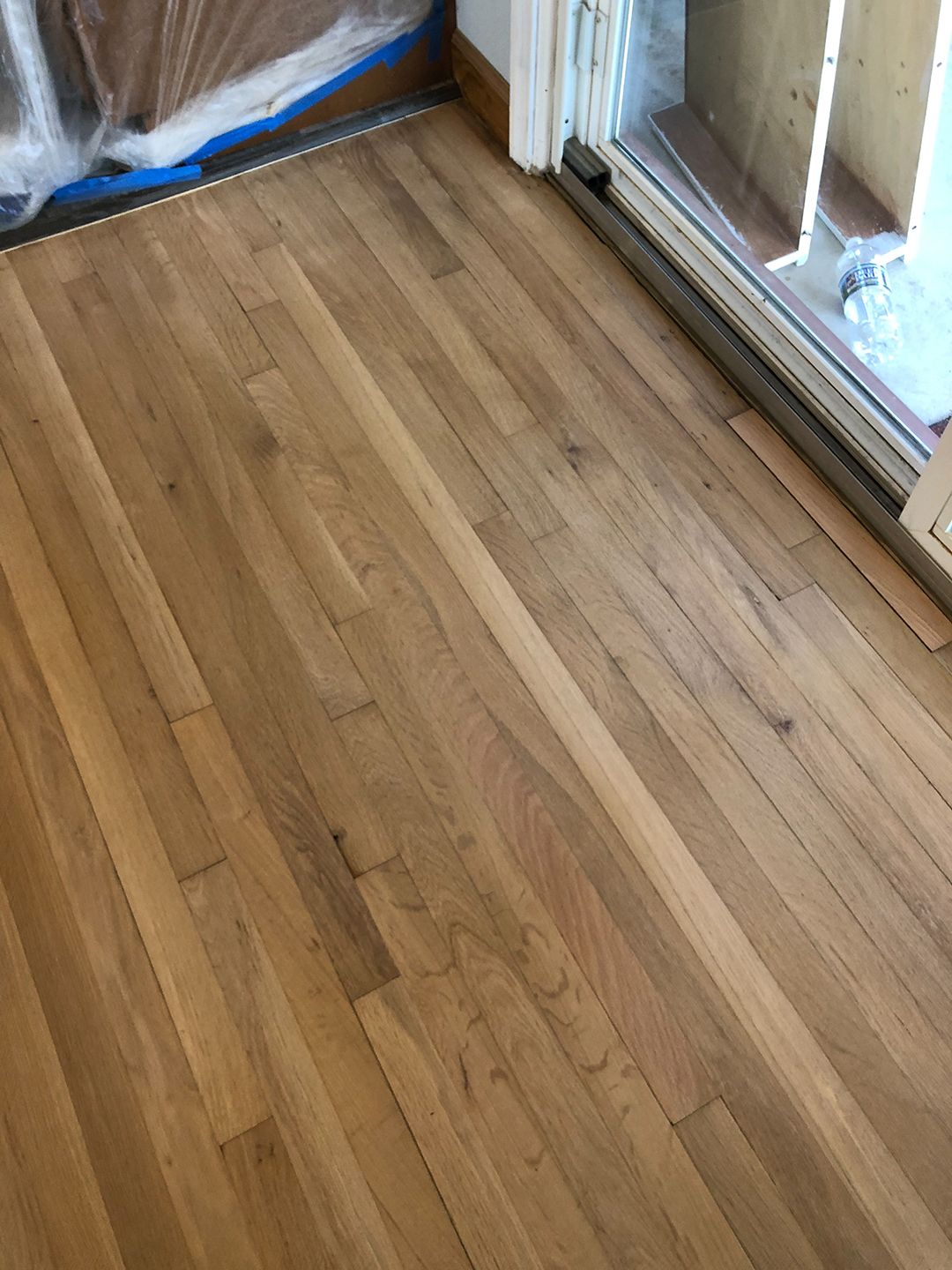 A wooden floor in a room with a sliding glass door.