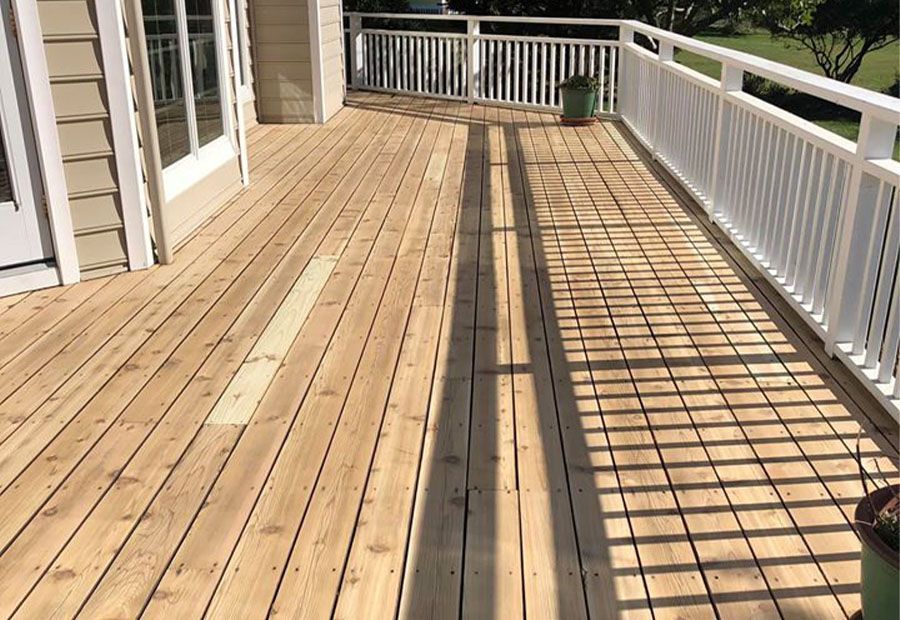 A wooden deck with a white railing and a potted plant on it.