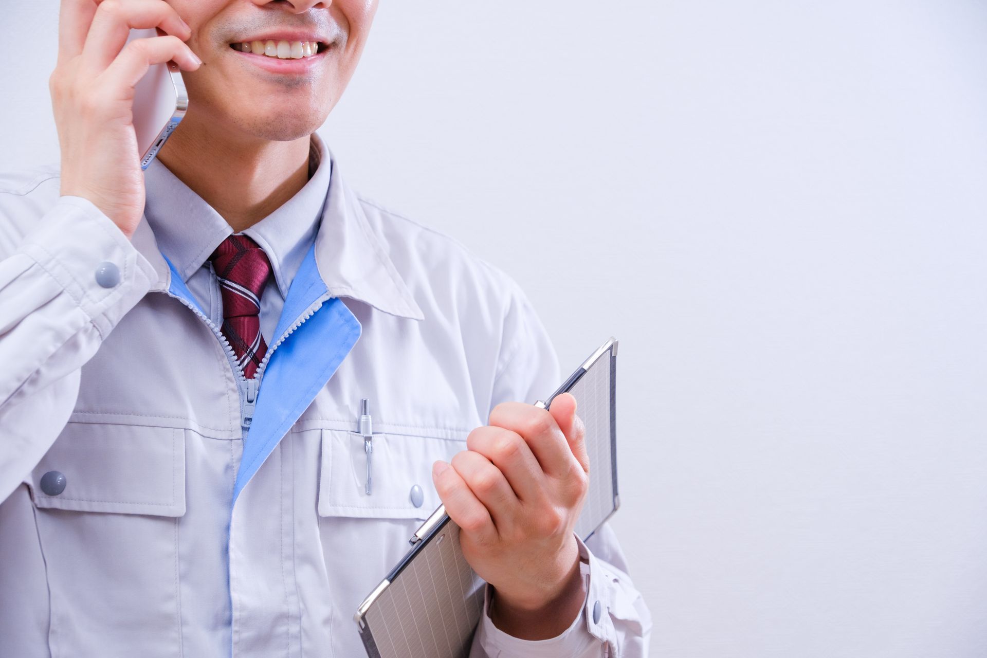 Doctor in a white coat speaking on a phone while holding a clipboard and pen. Doctor in a white coat speaking on a phone while holding a clipboard and pen.