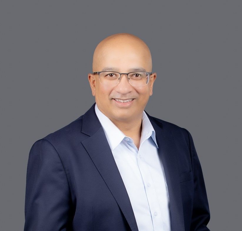 A bald man wearing glasses and a suit is smiling for the camera.