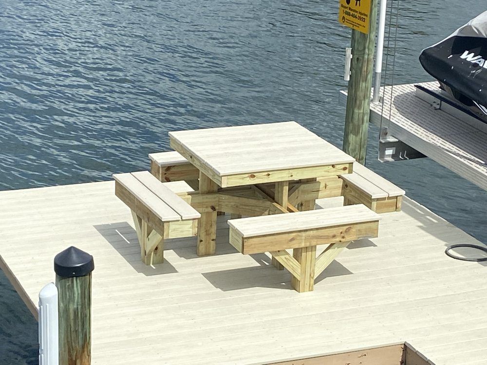 Picnic table on a dock by water, with attached benches. Wooden construction.