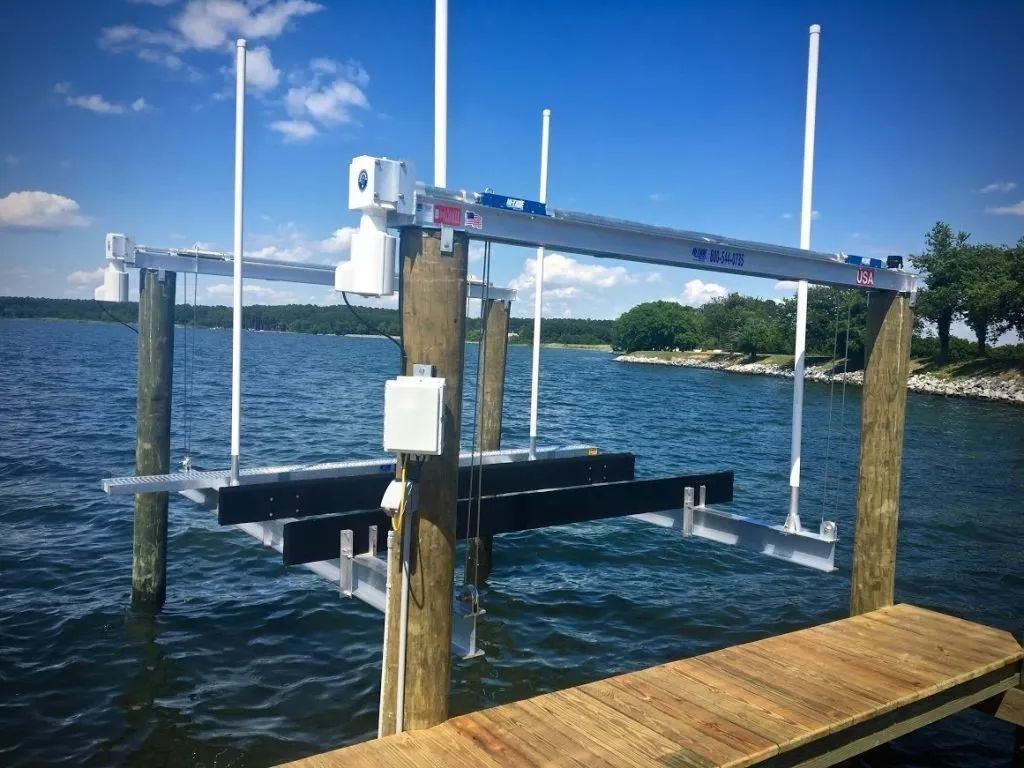 Boat lift on wooden pilings in a lake, with blue water and trees in the background.