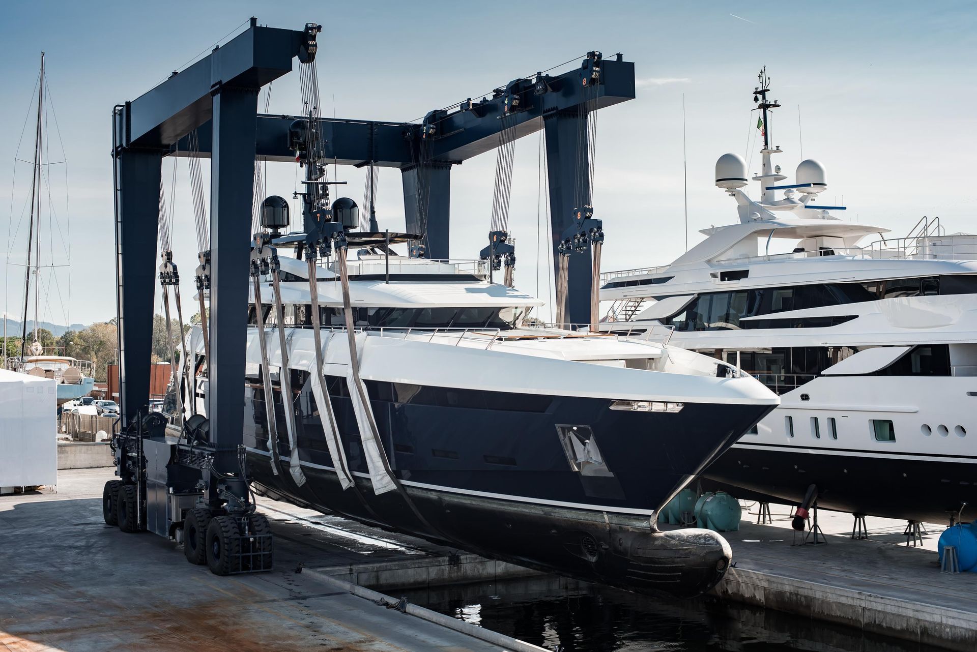 Large crane lifting a blue and white yacht at a marina.